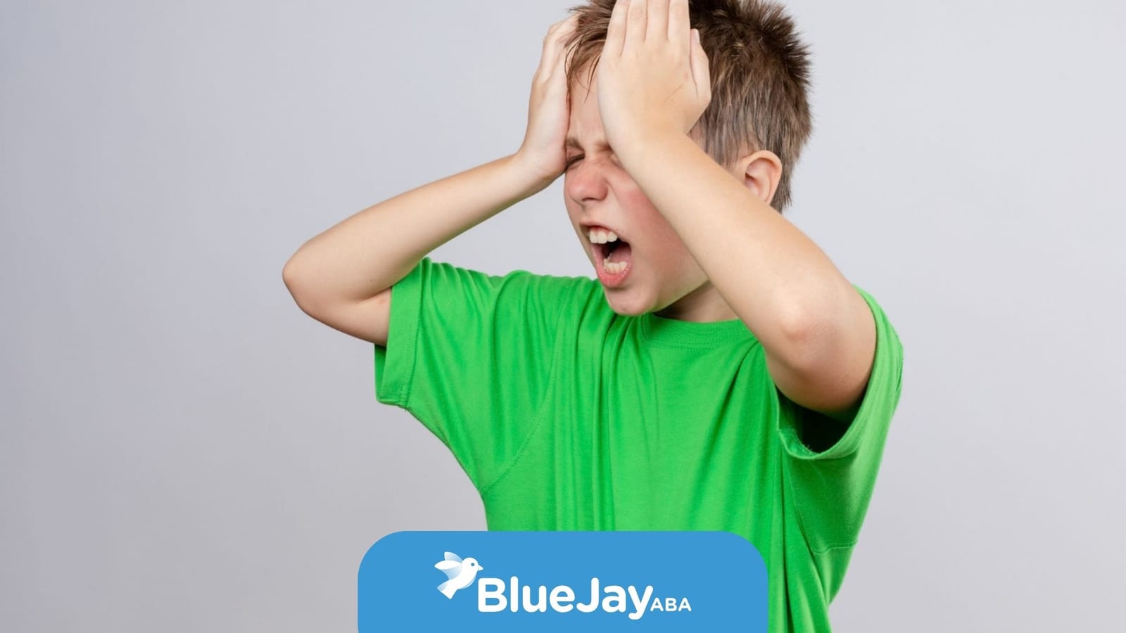 Young boy with autism holding his head and shouting during an emotional outburst.