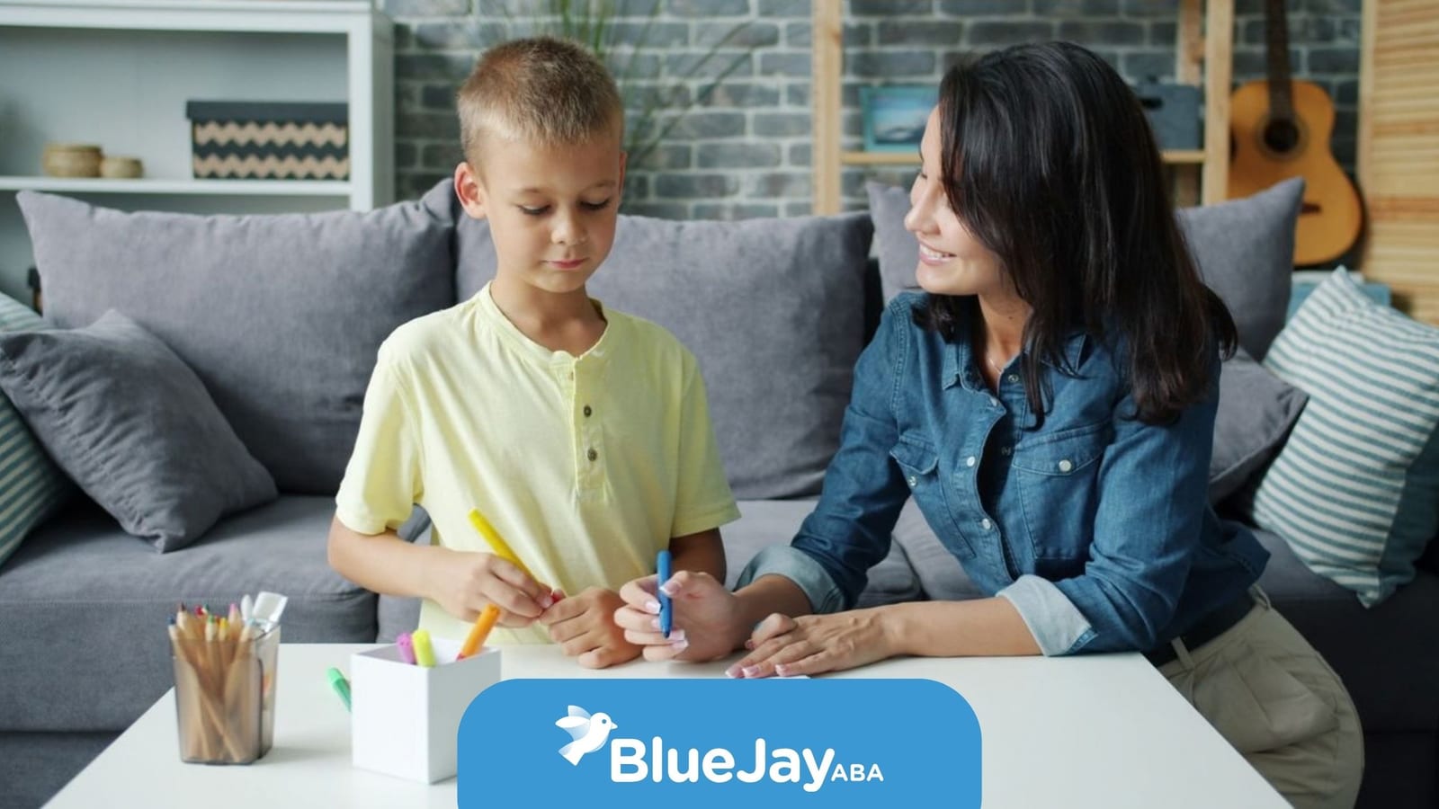 Therapist helping a young boy draw during an at-home ABA therapy session.