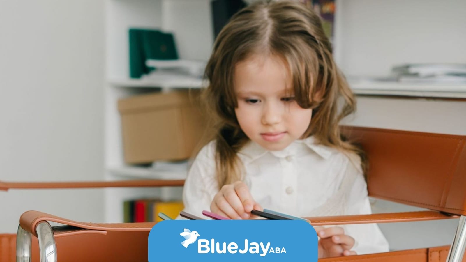 Child arranging colored pencils during an autism therapy or learning activity.
