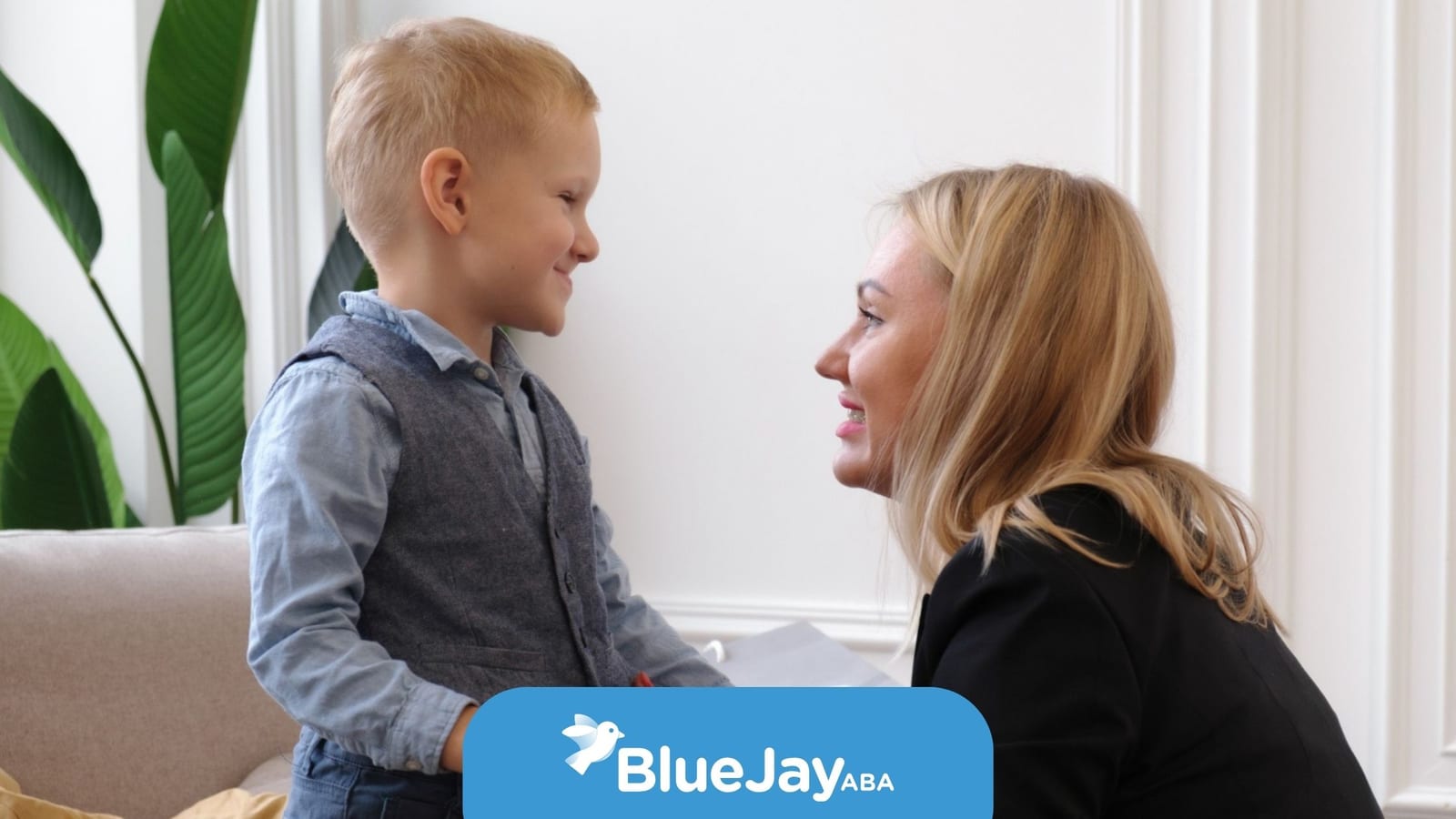 Young boy smiling at a woman during a supportive ABA therapy interaction.