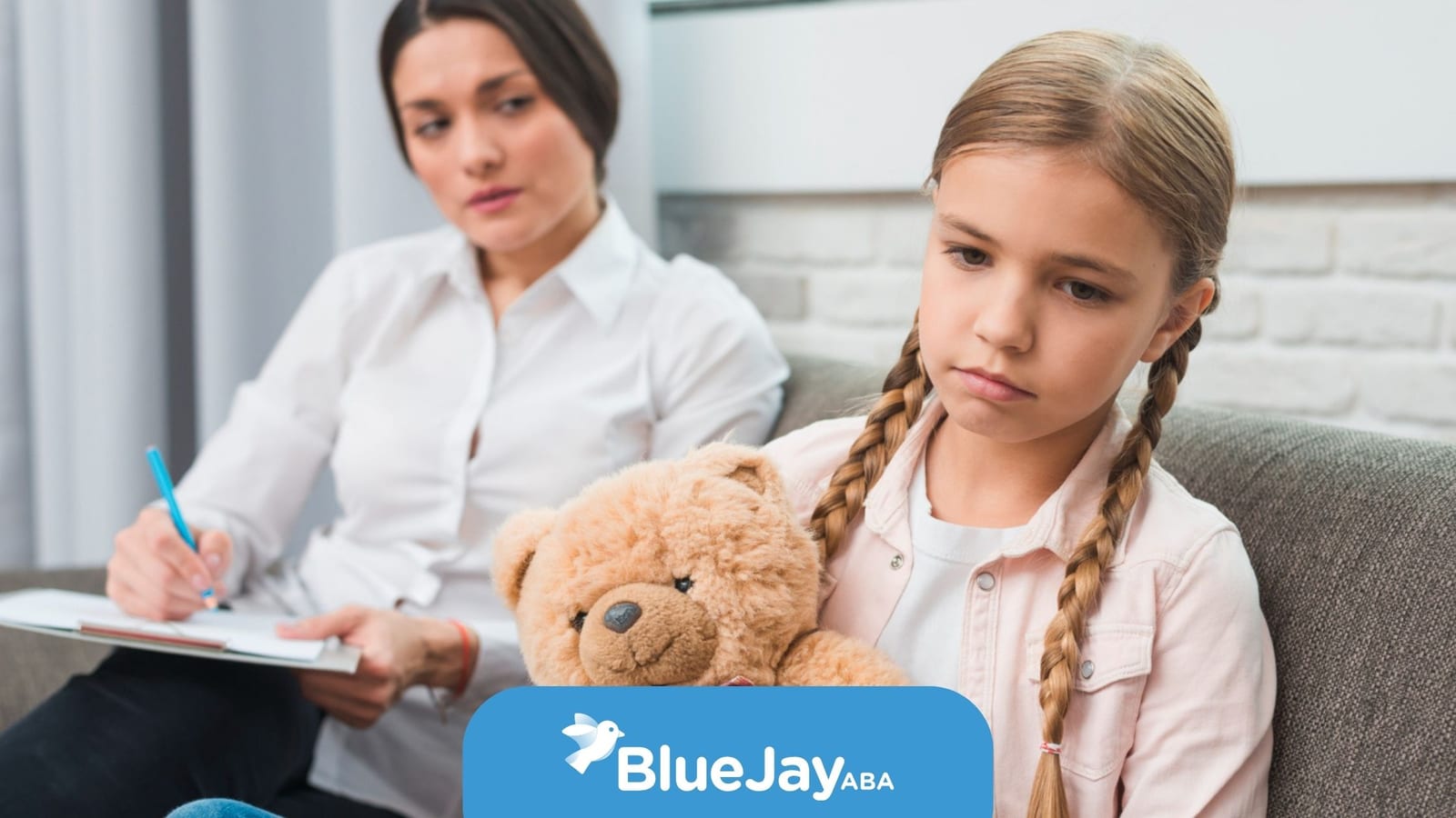 Girl holding a teddy bear during an ABA therapy session.